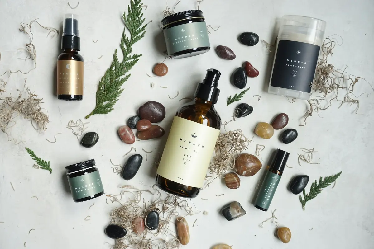 Skincare products arranged with smooth river stones and evergreen sprigs