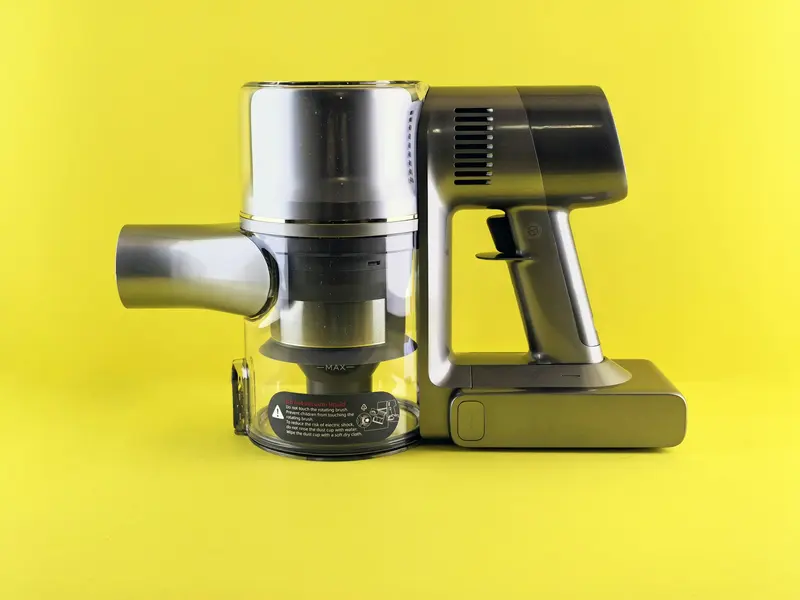 A person using a cordless vacuum along a wall