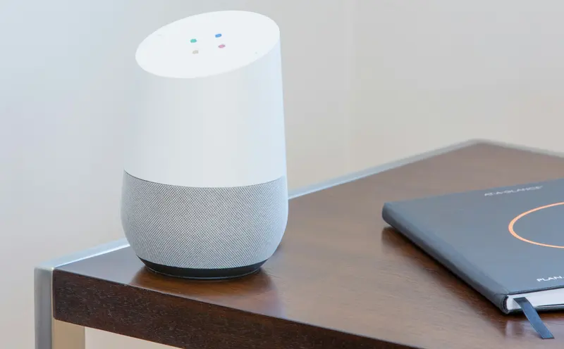 A white and gray smart speaker on a wooden table