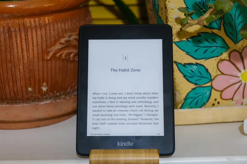 A person holding an e-reader on a table