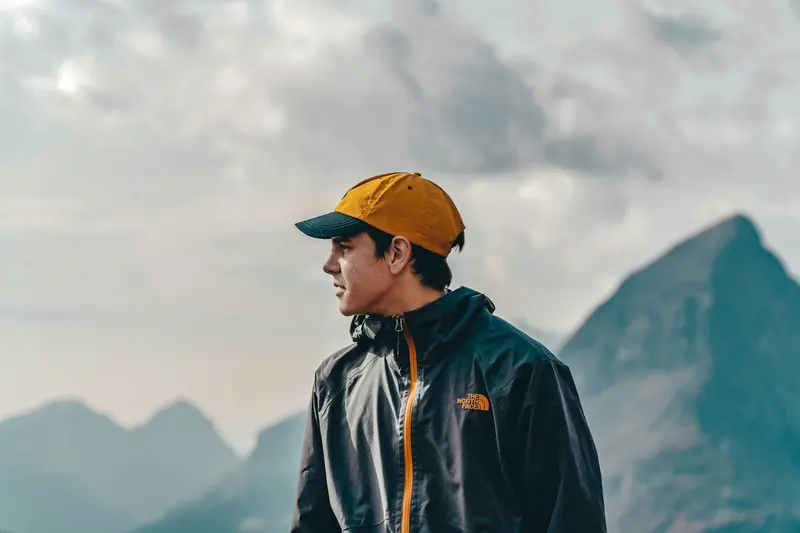 A hiker in a blue jacket standing above a mountain valley